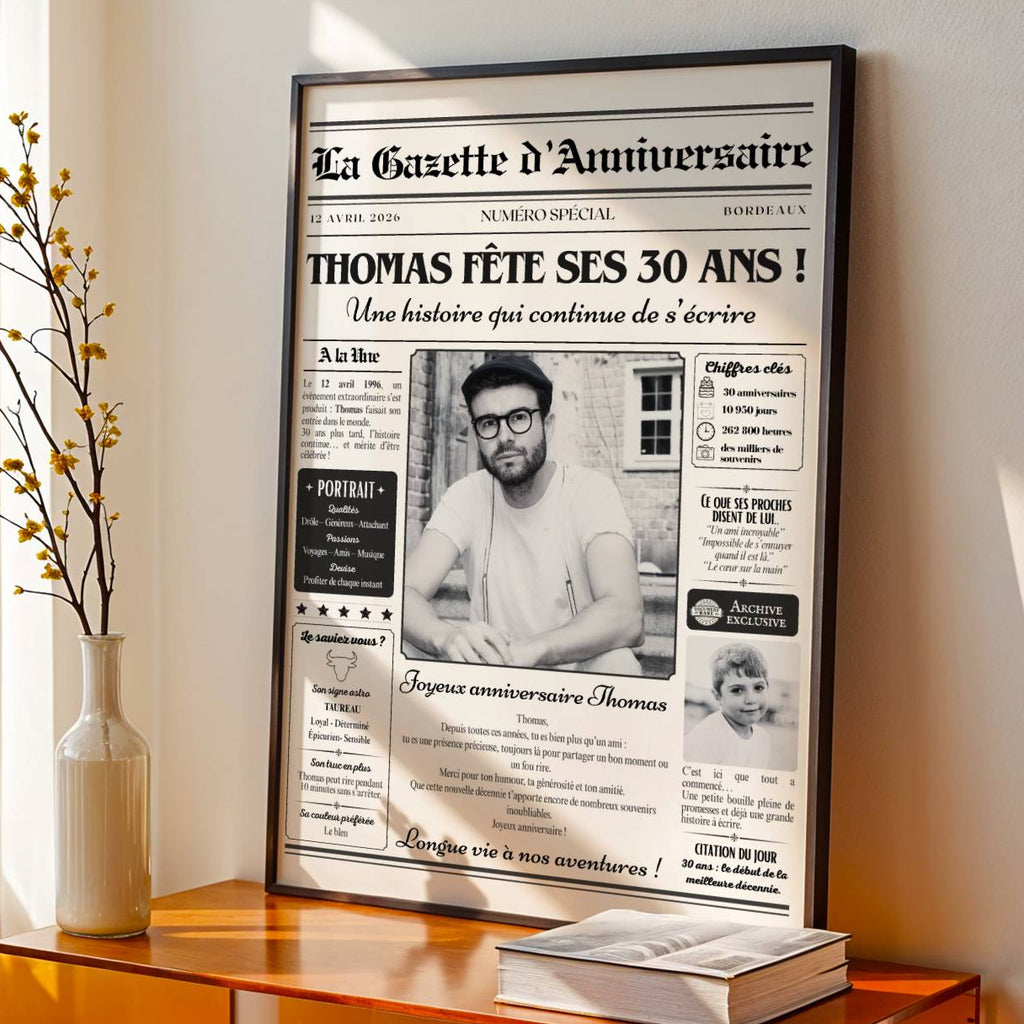 Gazette anniversaire personnalisée pour les 30 ans d'un homme, avec prénom et photos souvenirs, dans un cadre noir sur un meuble.